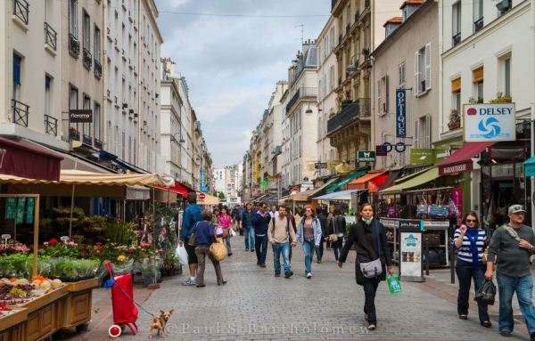 La rue Cler est une rue animée et joyeuse garnie de petits restos, de cafés, de terrasses, de marchés, de boulangeries et autres bonheurs. 